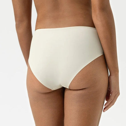 Person wearing a light-colored bra and high-waisted underwear on a white background