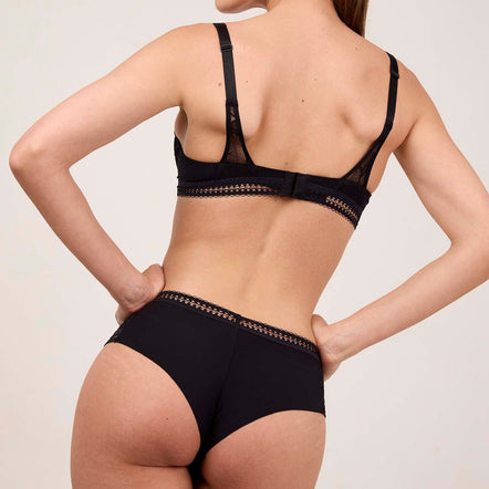 Woman wearing a black lingerie set on a plain background