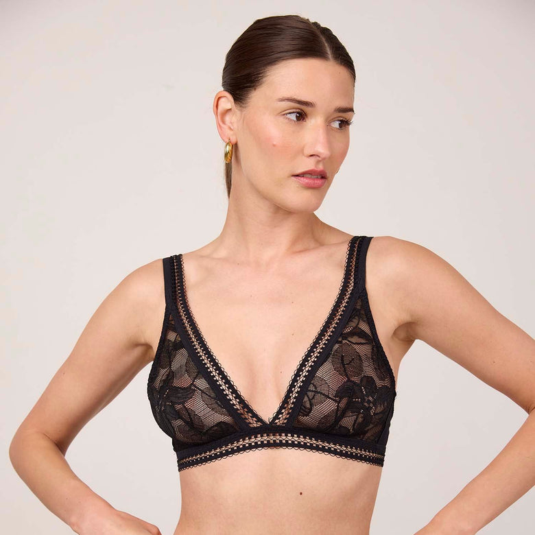 Woman wearing a black lace lingerie set against a plain background