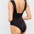 Black swimsuit worn by a model on a light gray background