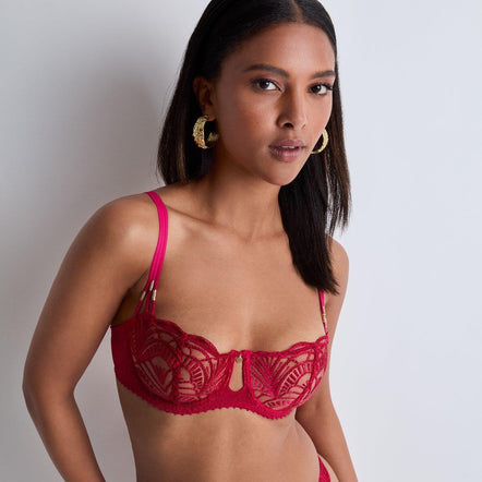 Woman wearing a red lace lingerie set against a plain background