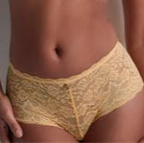 Woman wearing a yellow bra and panties set against a plain background