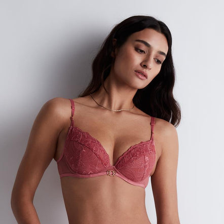 Woman wearing a red lace lingerie set against a plain background