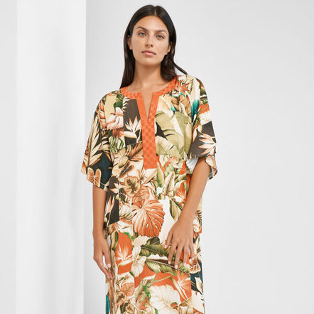 Woman wearing a floral dress with an orange top against a white background