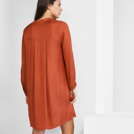 Woman wearing a rust-colored dress on a white background