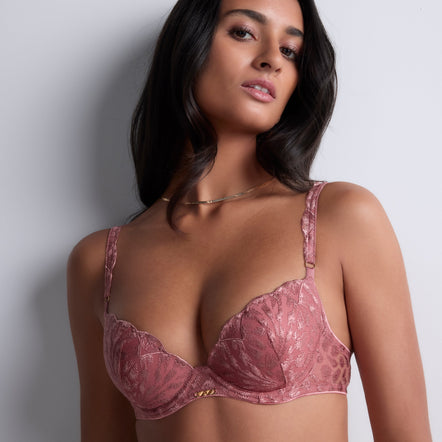 Woman wearing a pink lace bra against a plain background