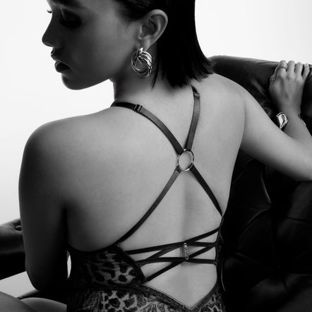 Woman wearing a leopard print bodysuit with a strappy back design, sitting on a couch.
