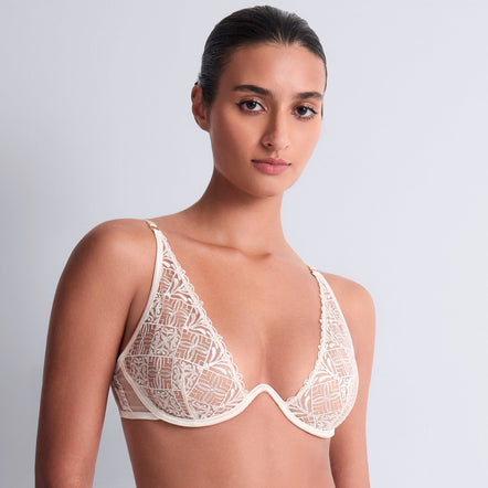 Woman wearing a white lace lingerie set against a plain background