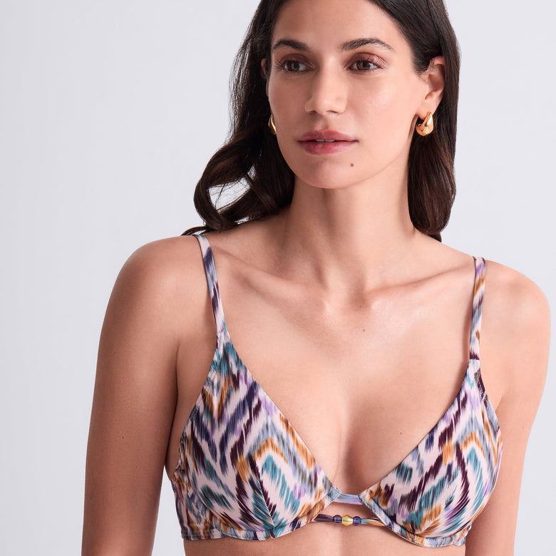 Woman wearing a patterned bikini top against a light gray background