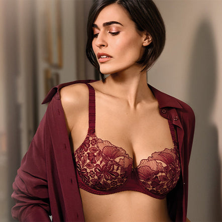 Woman wearing a red lace bralette with a matching cardigan against a neutral background