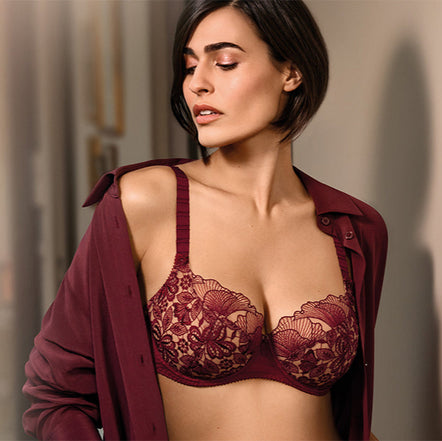 Woman wearing a red lace bralette with a matching cardigan against a neutral background