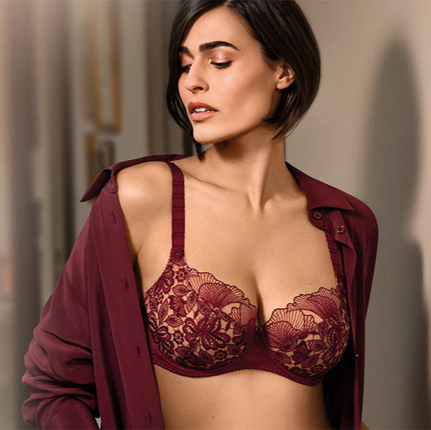 Woman wearing a red lace bralette with a matching cardigan against a neutral background