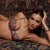 A woman reclining on a patterned rug wearing a purple and beige paisley lingerie set with matching garter straps.