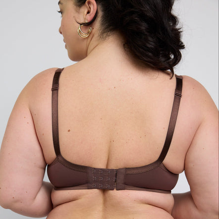 A woman shown from the back wearing a brown bra and matching high-waisted briefs against a light gray studio background.
