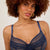 Woman wearing a navy blue lace bra against a plain background