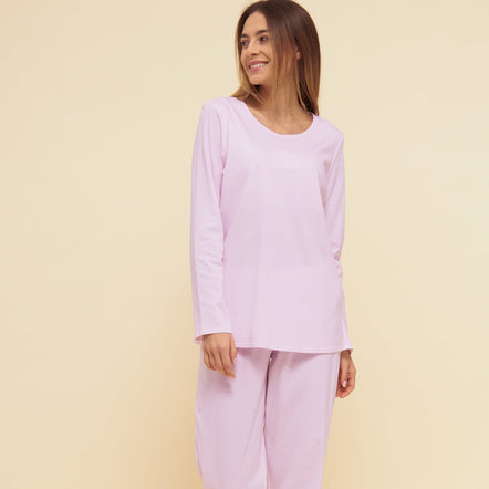 Woman wearing a light pink pajama set against a beige background