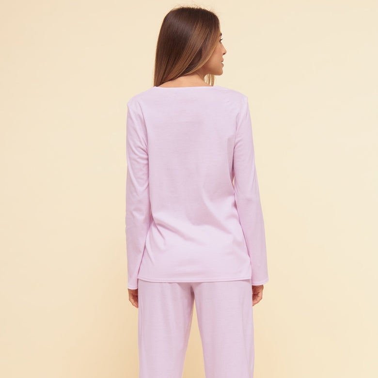 Woman wearing a light purple pajama set on a beige background