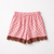 Pink shorts with bow pattern and lace trim on a white background