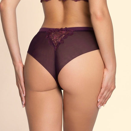 Woman wearing a purple lingerie set on a beige background