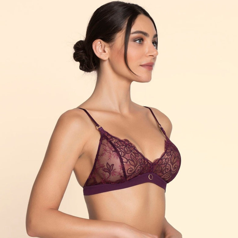 Woman wearing a dark purple lace lingerie set on a beige background