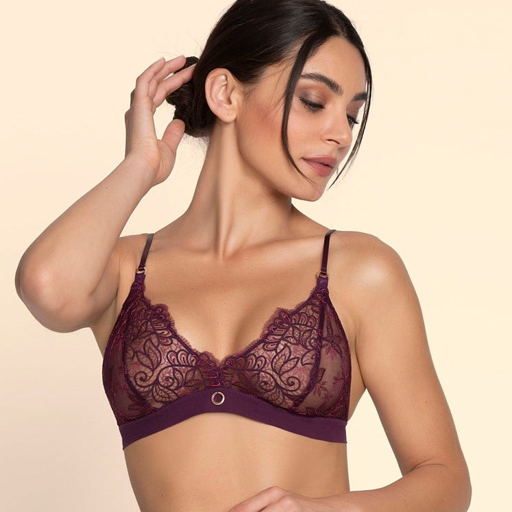 Woman wearing a dark purple lace lingerie set on a beige background