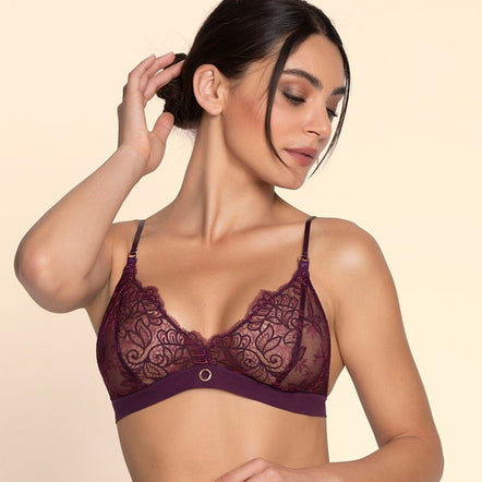 Woman wearing a dark purple lace lingerie set on a beige background
