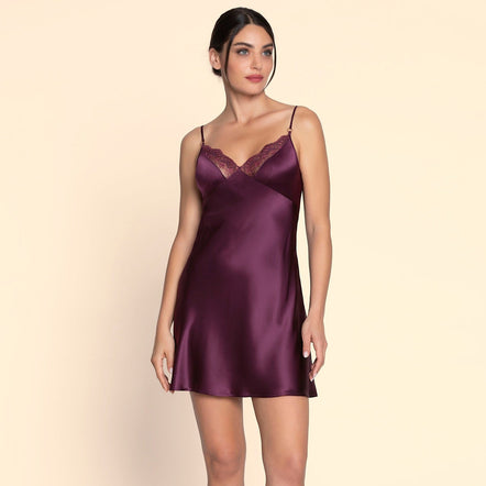 Woman wearing a purple satin slip against a beige background