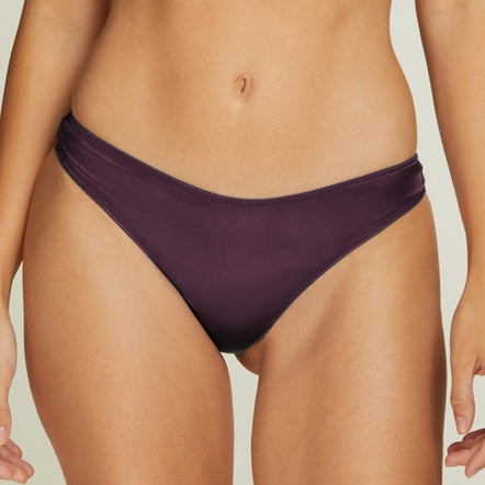 Woman wearing a purple bikini set on a beige background