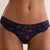 A close-up of a model's lower torso wearing navy blue lace panties with a small gold paperclip detail at the center front, against a plain light beige background.