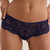 A close-up of a model wearing navy blue lace panties with a small gold metal clasp at the center front, paired with a matching navy lace bra top, against a light beige background.