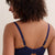 A woman shown from the back wearing a navy blue lace bralette and matching lace panties against a plain light beige studio background.