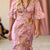 Model wearing a pink floral dress and hat on a fashion runway.