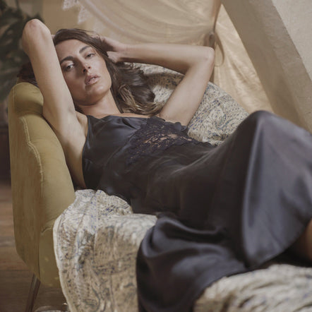 Woman in a black dress lying on a patterned chair with a disco ball in the foreground.