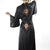 Black satin robe with lace detailing worn by a model on a white background