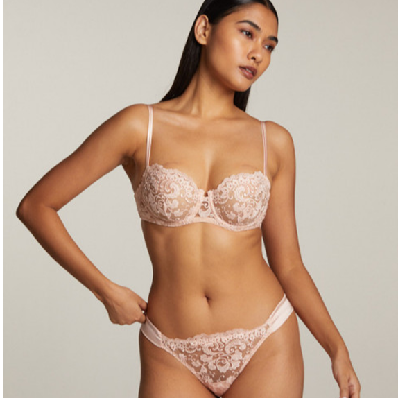 Woman wearing a lace bra and panties set against a neutral background