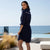 Woman in a navy blue dress standing on a patio with ocean view