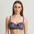 A woman modeling a navy blue lace lingerie set consisting of a sheer underwire bra and matching high-waisted briefs against a light gray studio background.