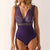 Purple lace bodysuit worn by a model on a plain background
