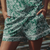 Green and white floral patterned shorts worn by a person with a blurred natural background