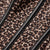 Close-up of a leopard print fabric with black leather-like trim running diagonally across the frame.