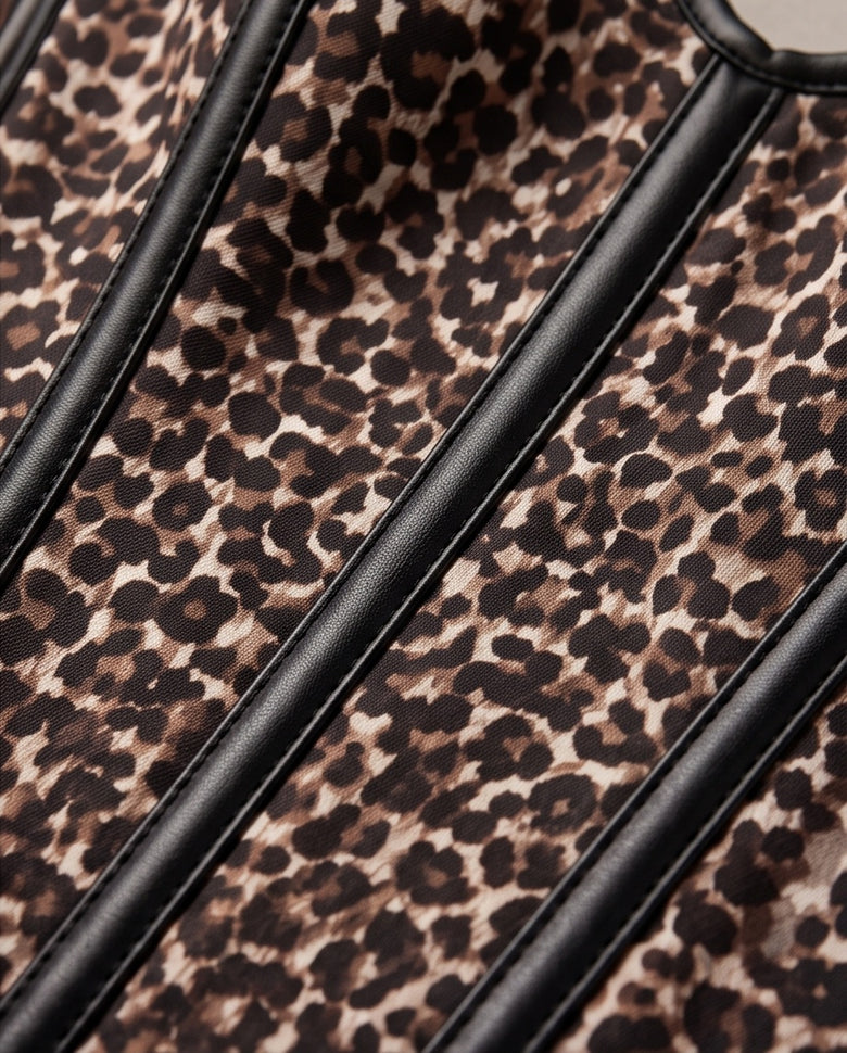 Close-up of a leopard print fabric with black leather-like trim running diagonally across the frame.