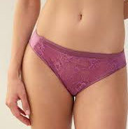 A close-up of a model wearing a pair of purple lace panties against a light beige background.