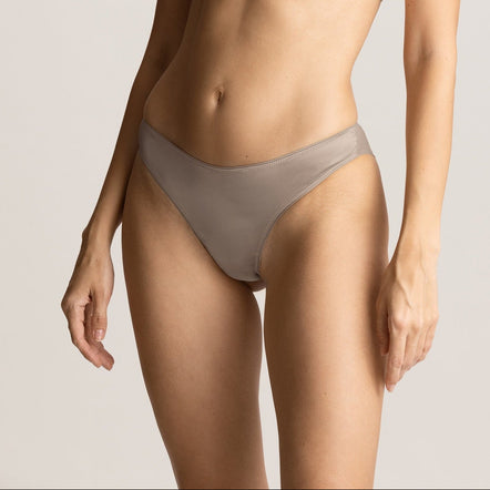 Woman wearing a beige bra and panties set against a plain background