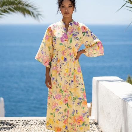 Woman in a floral dress standing on a balcony with ocean view