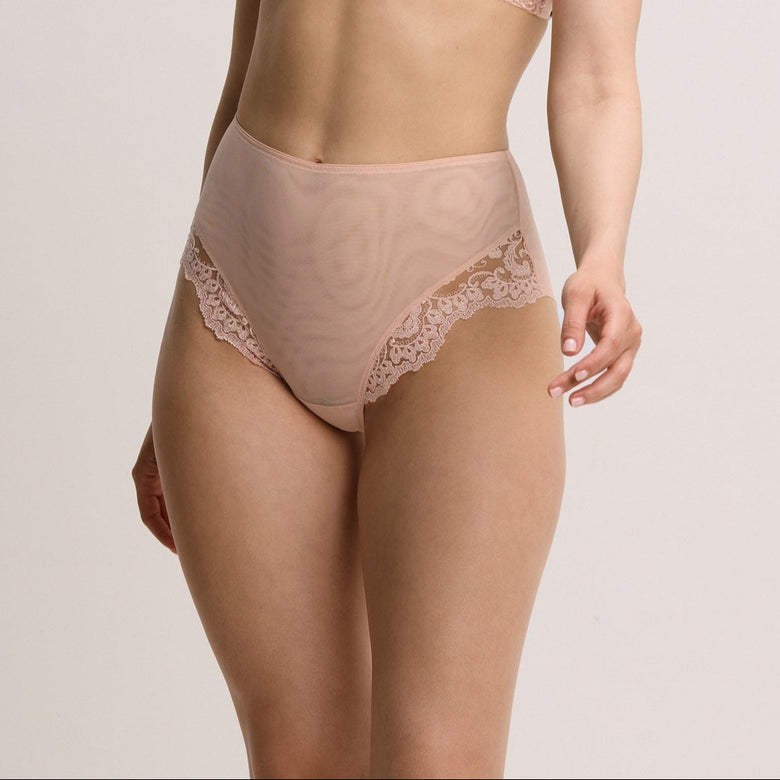 Woman wearing a beige lace lingerie set on a plain background