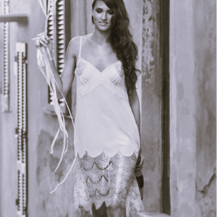 Woman in a vintage-style dress walking outdoors with a decorative umbrella.