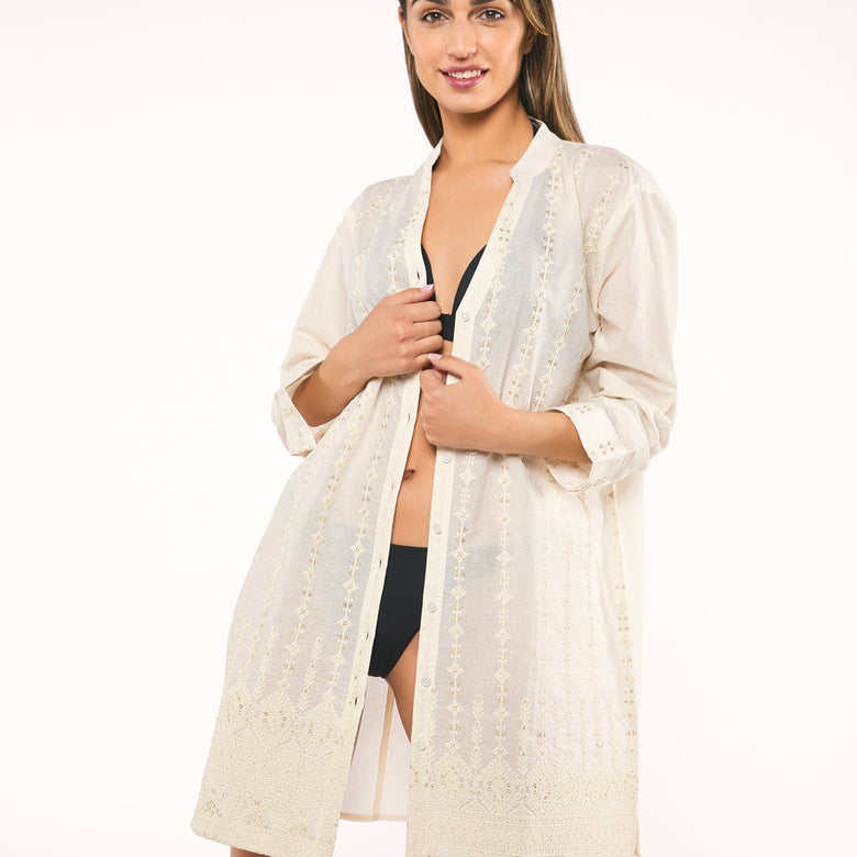 Woman wearing a white lace cover-up over a black bikini on a white background